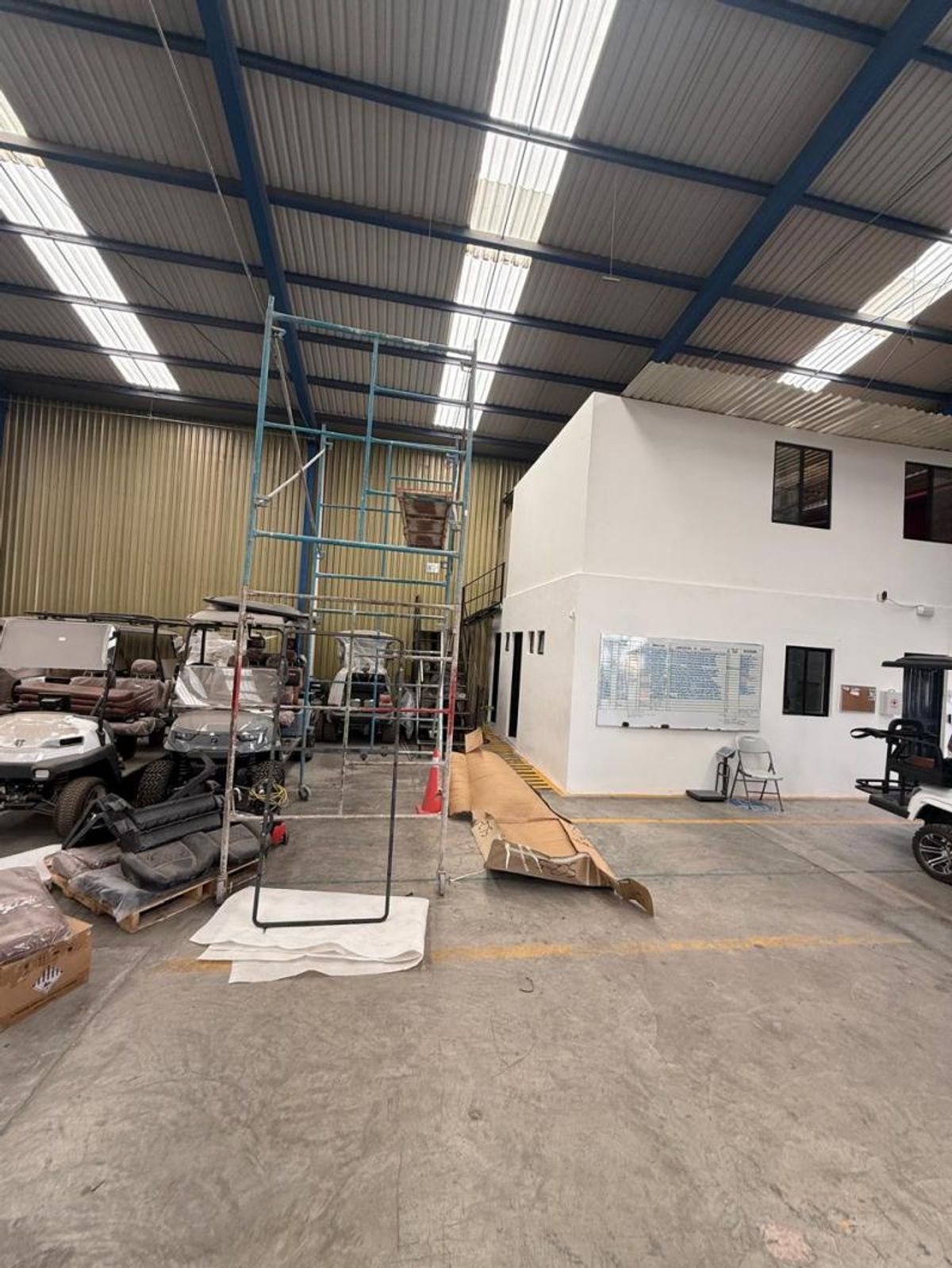 Interior de bodega con piso de concreto, techado metálico con tragaluces y oficinas interiores