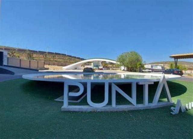 Letras blancas tridimensionales con la palabra PUNTA junto a un espejo de agua circular