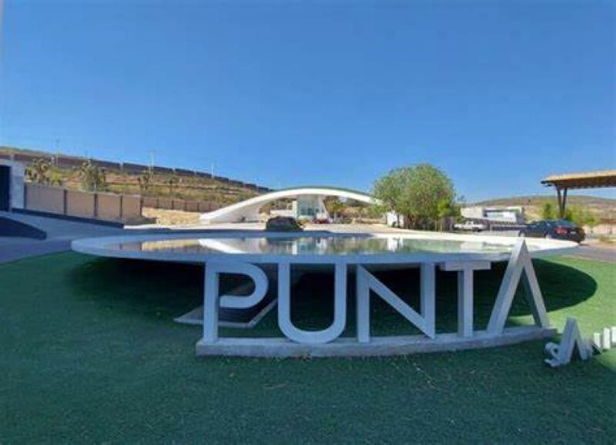 Letras blancas tridimensionales con la palabra PUNTA junto a un espejo de agua circular