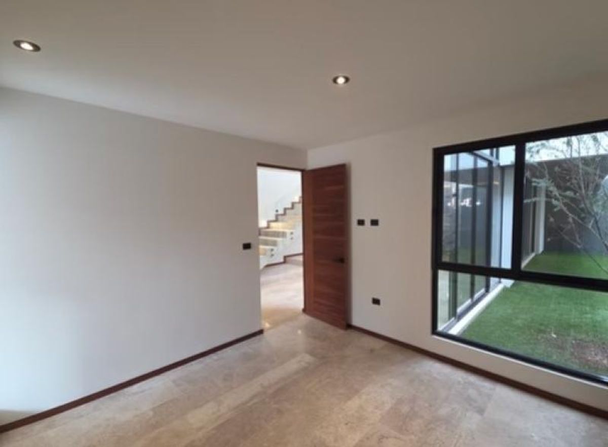 Habitación con piso de mármol, puerta de madera y ventanal con vista al jardín