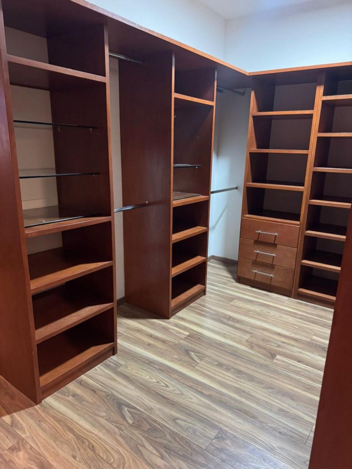 Vestidor de madera con repisas, cajones, tubos para colgar y piso tipo madera