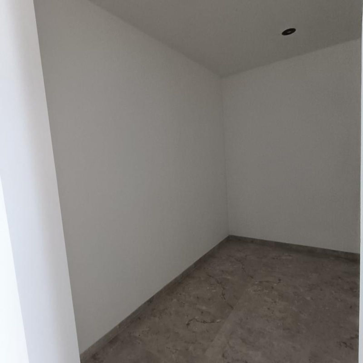 Espacio interior vacío con paredes blancas y piso de mármol veteado gris