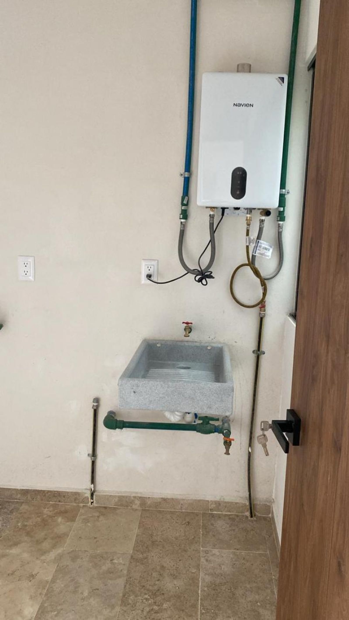 Área de lavado con calentador de agua de paso, lavadero de piedra y piso cerámico
