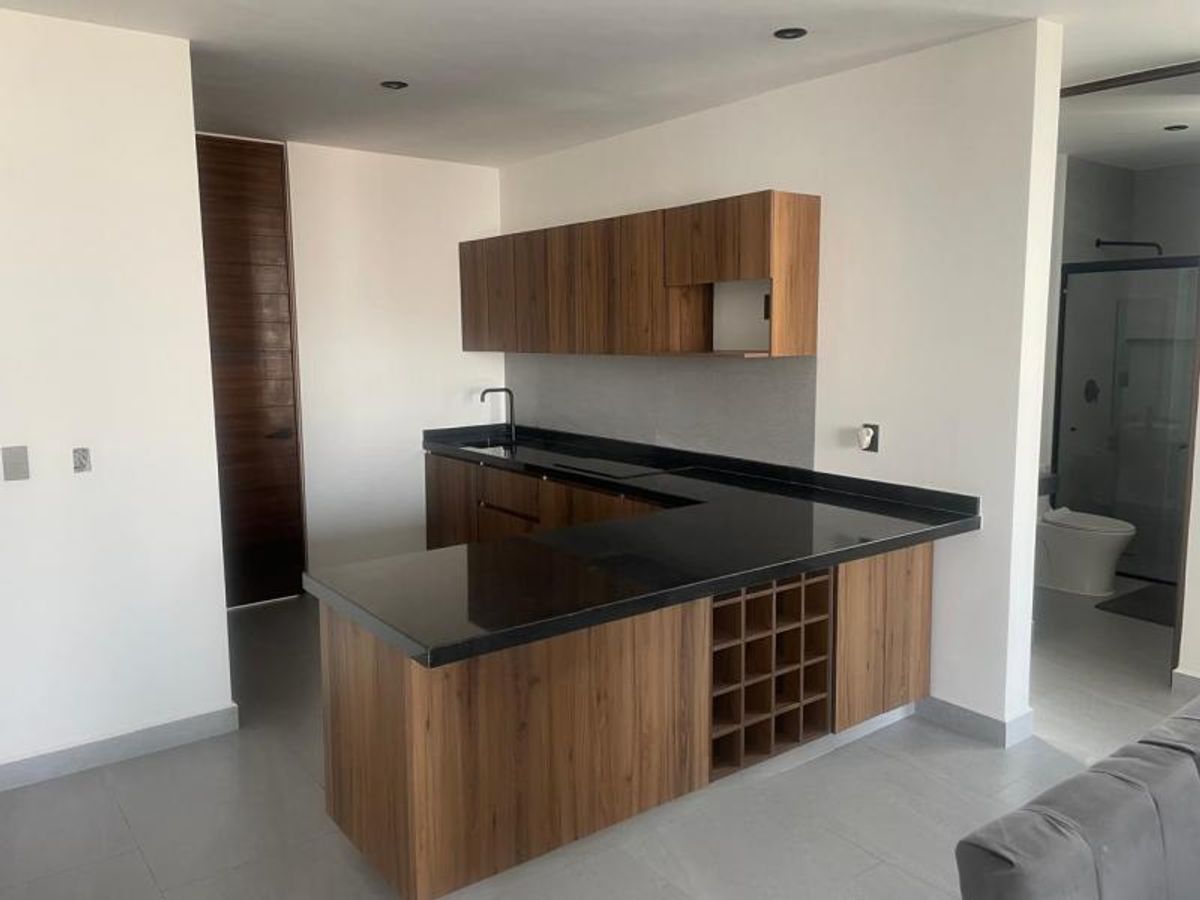 Cocina con cubierta de granito negro, gabinetes de madera, botellero integrado y piso gris