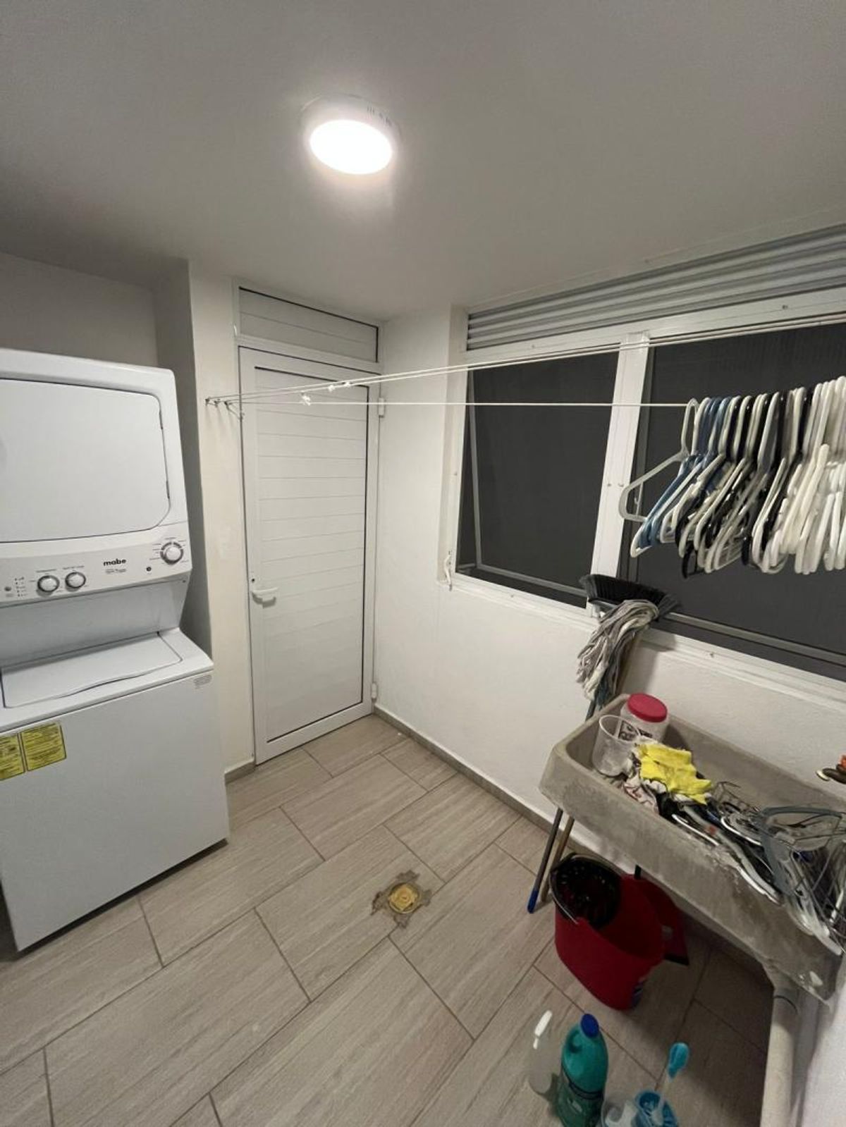Cuarto de lavado con centro de lavado blanco, lavadero y piso cerámico tipo madera
