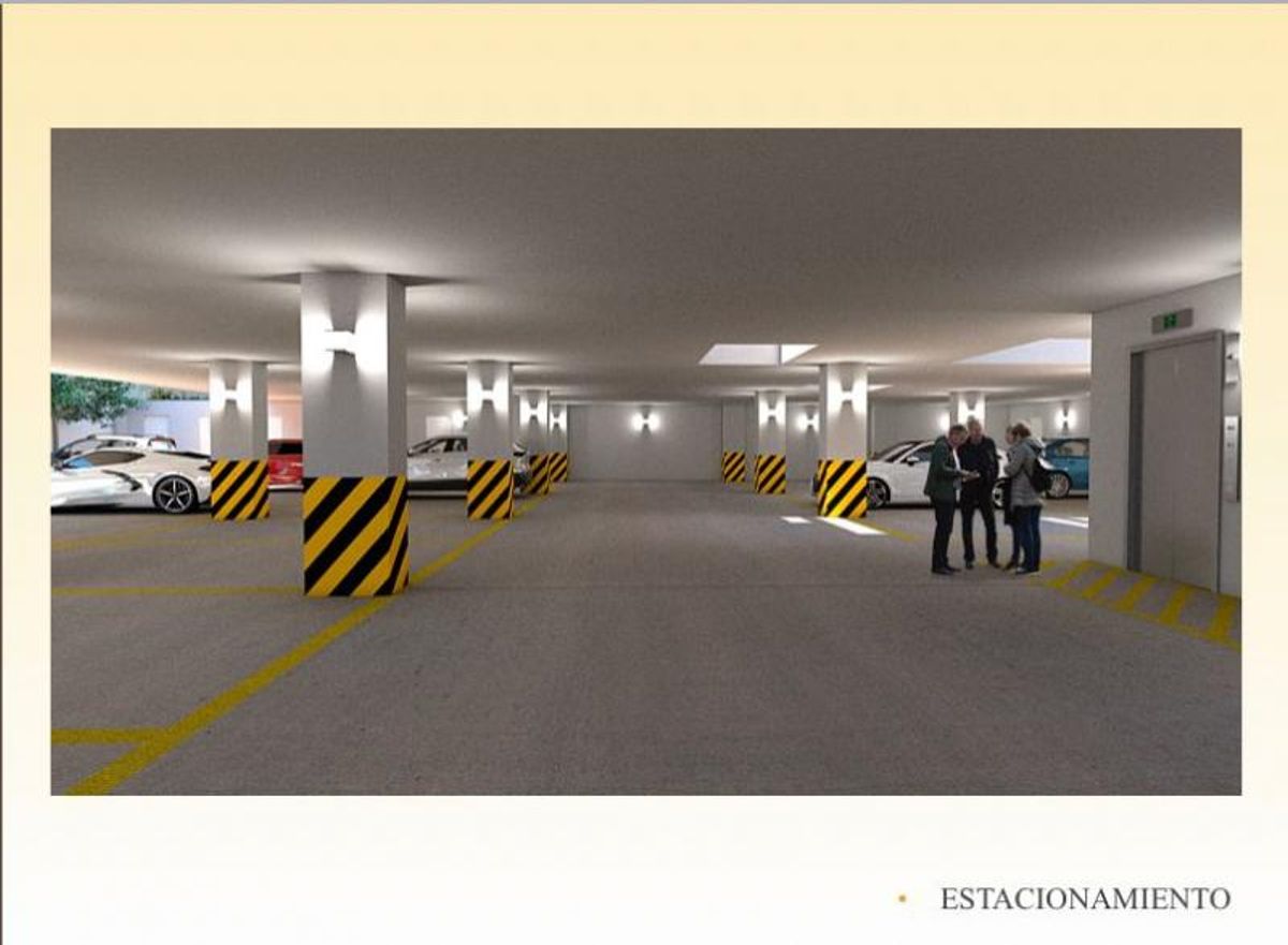 Estacionamiento techado con piso de concreto, cajones delimitados en amarillo y columnas iluminadas