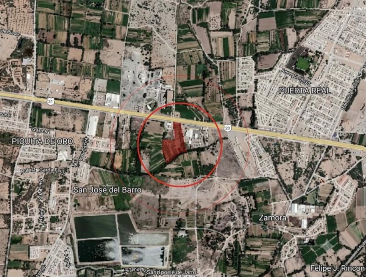 Terreno delimitado en rojo en mapa satelital junto a carretera principal y parcelas agrícolas