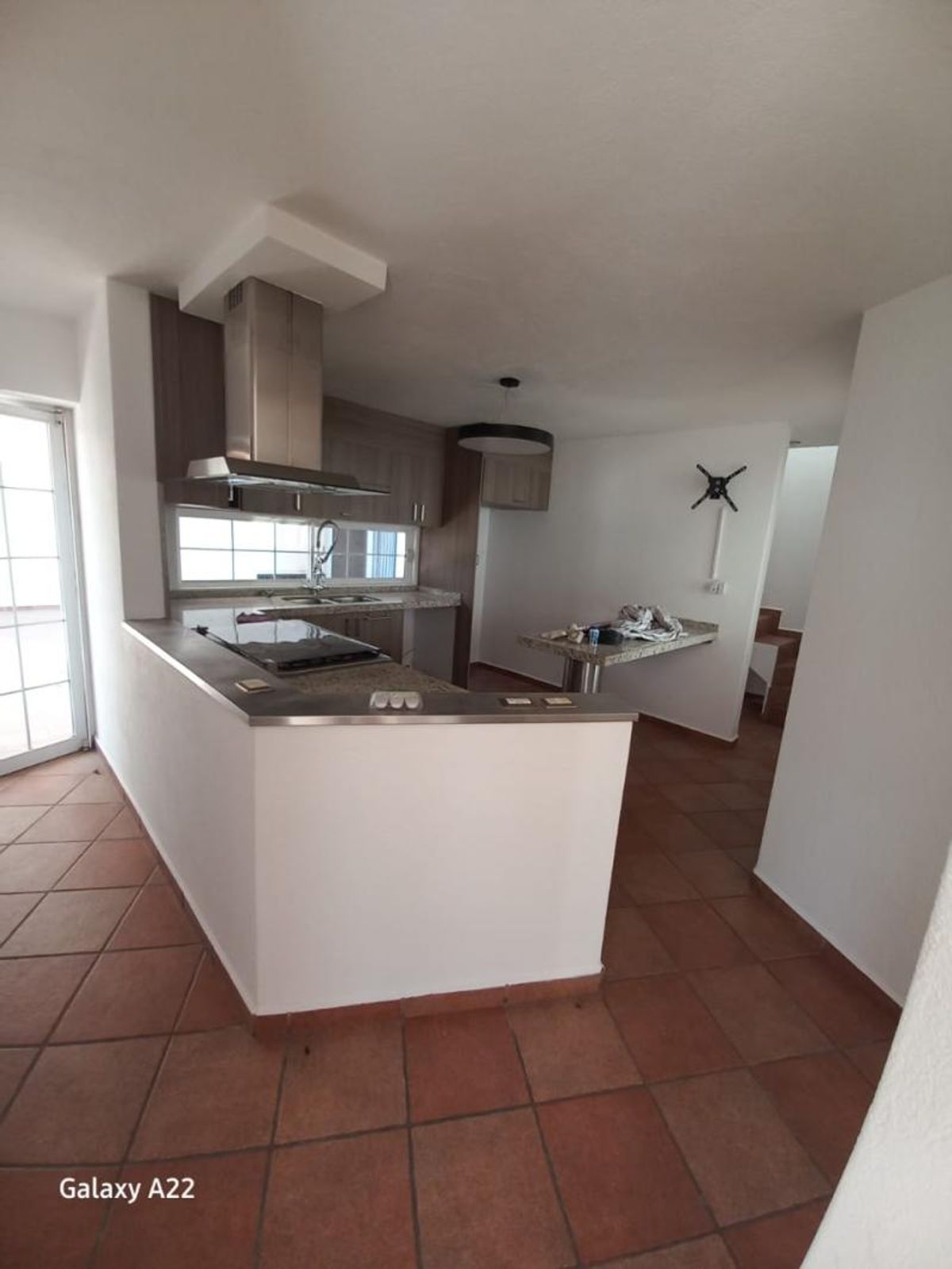 Cocina integral con barra, campana de acero inoxidable, gabinetes de madera y piso terracota