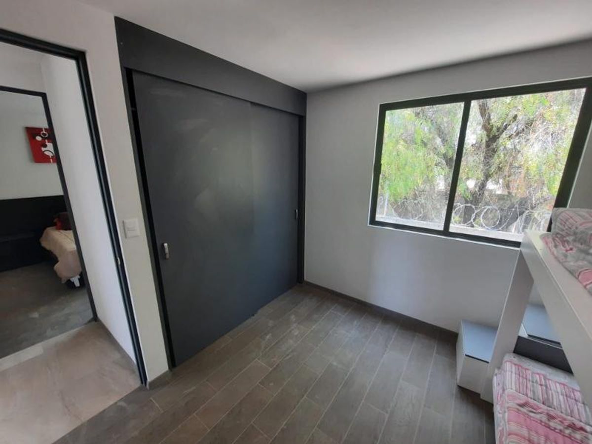Recámara con piso tipo madera, clóset de puertas corredizas oscuras, ventana y litera