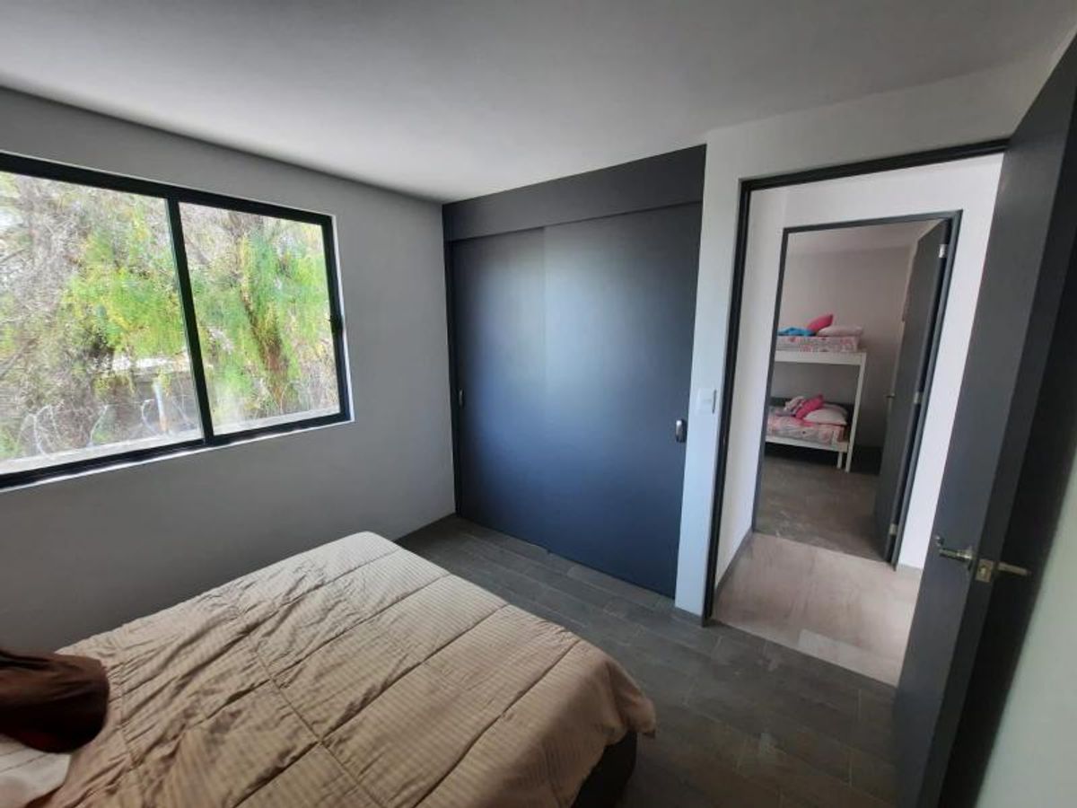 Recámara con cama, clóset de puertas corredizas oscuras, ventana exterior y piso cerámico