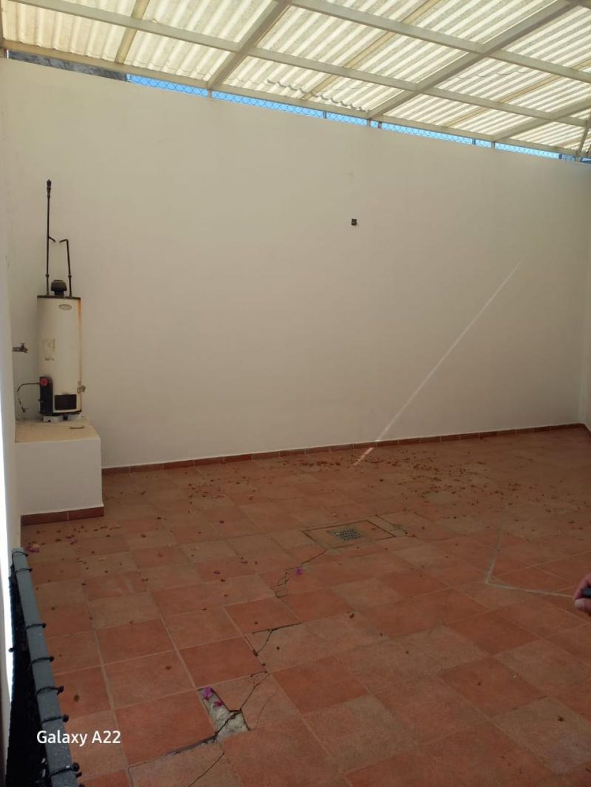 Patio cubierto con piso de cerámica terracota, calentador de agua y techo traslúcido