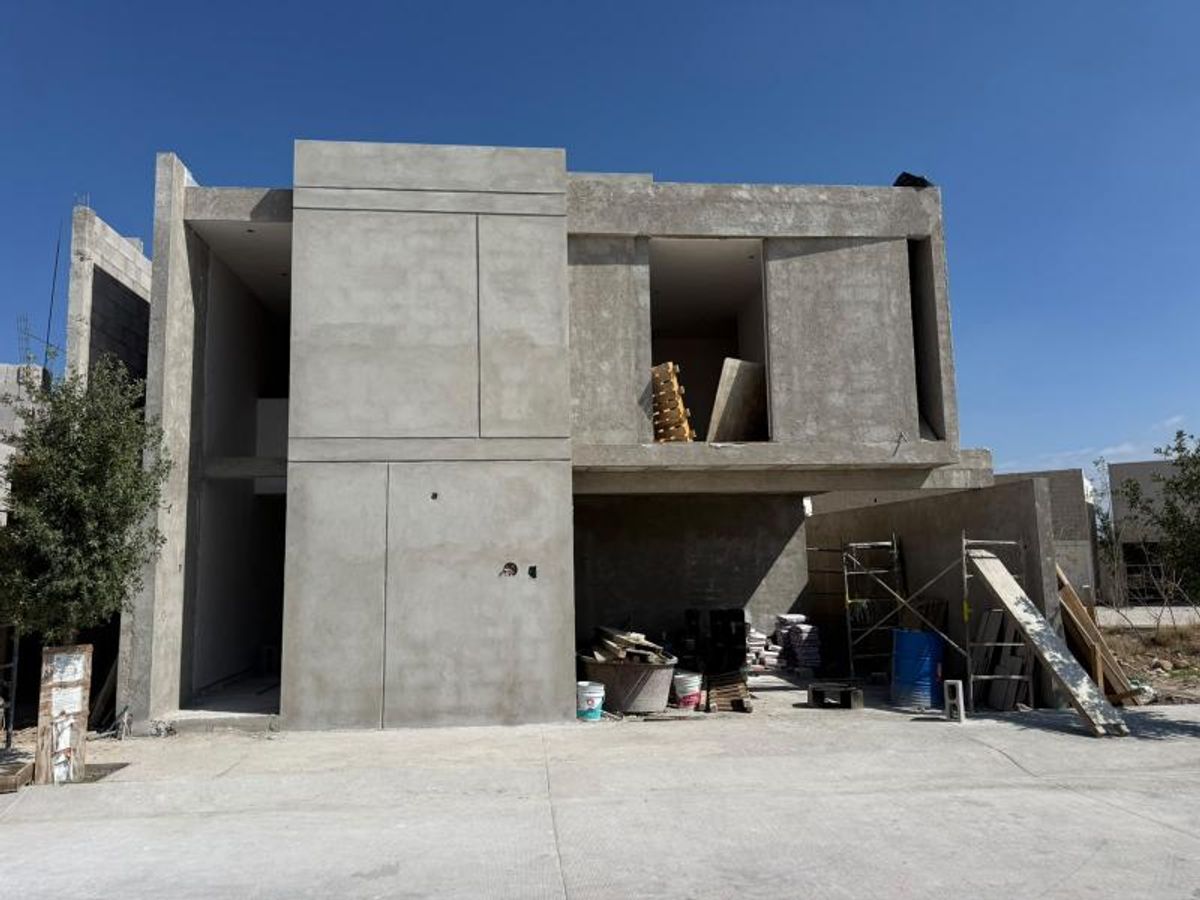 Casa en obra gris de dos niveles con fachada de concreto y materiales de construcción