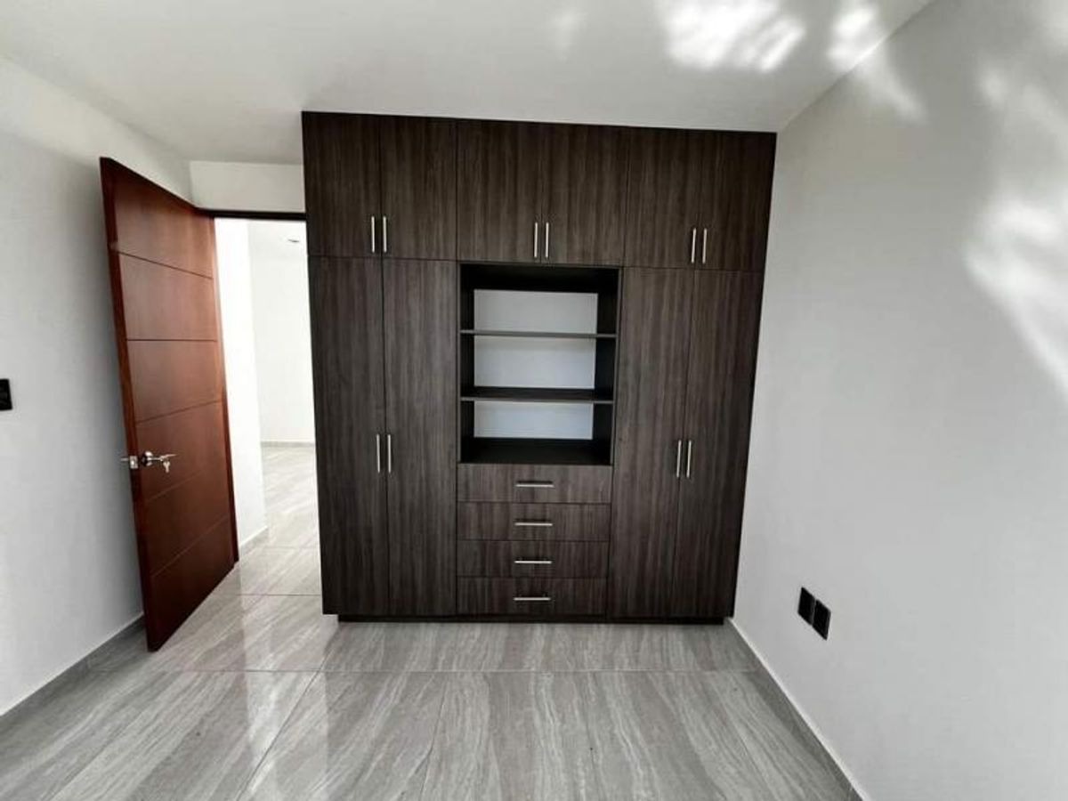 Closet de madera oscura con repisas y cajones junto a puerta de madera abierta