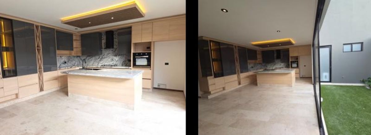 Cocina integral con isla central, gabinetes de madera y ventanal hacia el jardín