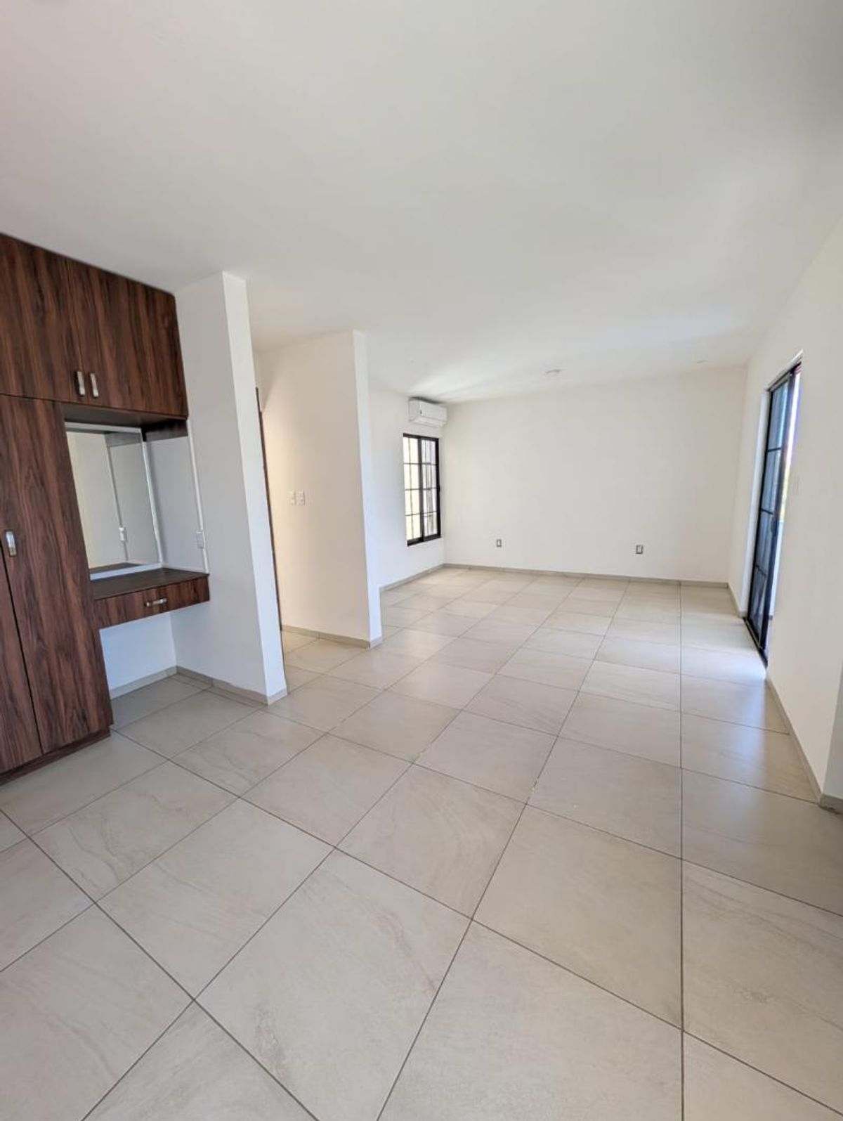 Habitación con piso de azulejo beige, paredes blancas y armario de madera con tocador integrado