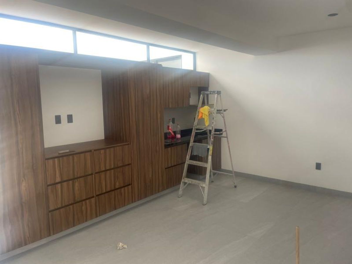 Interior con mueble empotrado de madera, paredes blancas y ventanales superiores alargados
