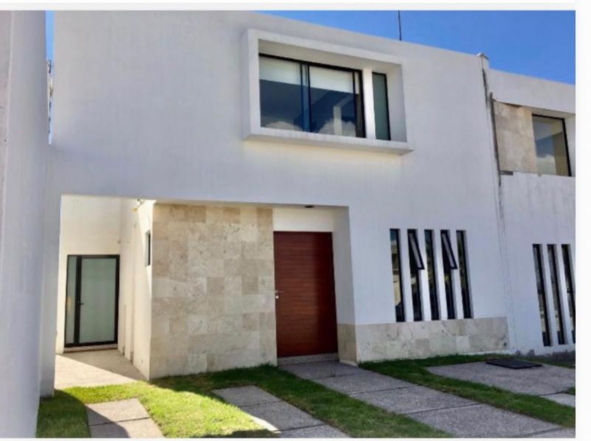 Fachada blanca moderna con puerta de madera, muro revestido de piedra y ventanas verticales