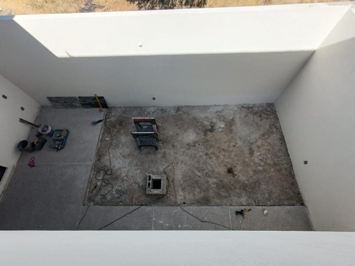 Patio interior con altos muros blancos y piso de concreto en proceso de acabado