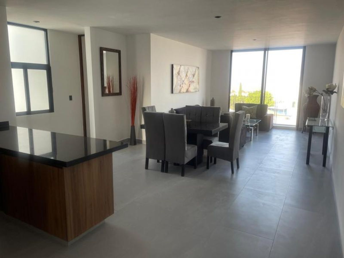 Comedor con sillas tapizadas grises, barra de madera y ventanales con luz natural