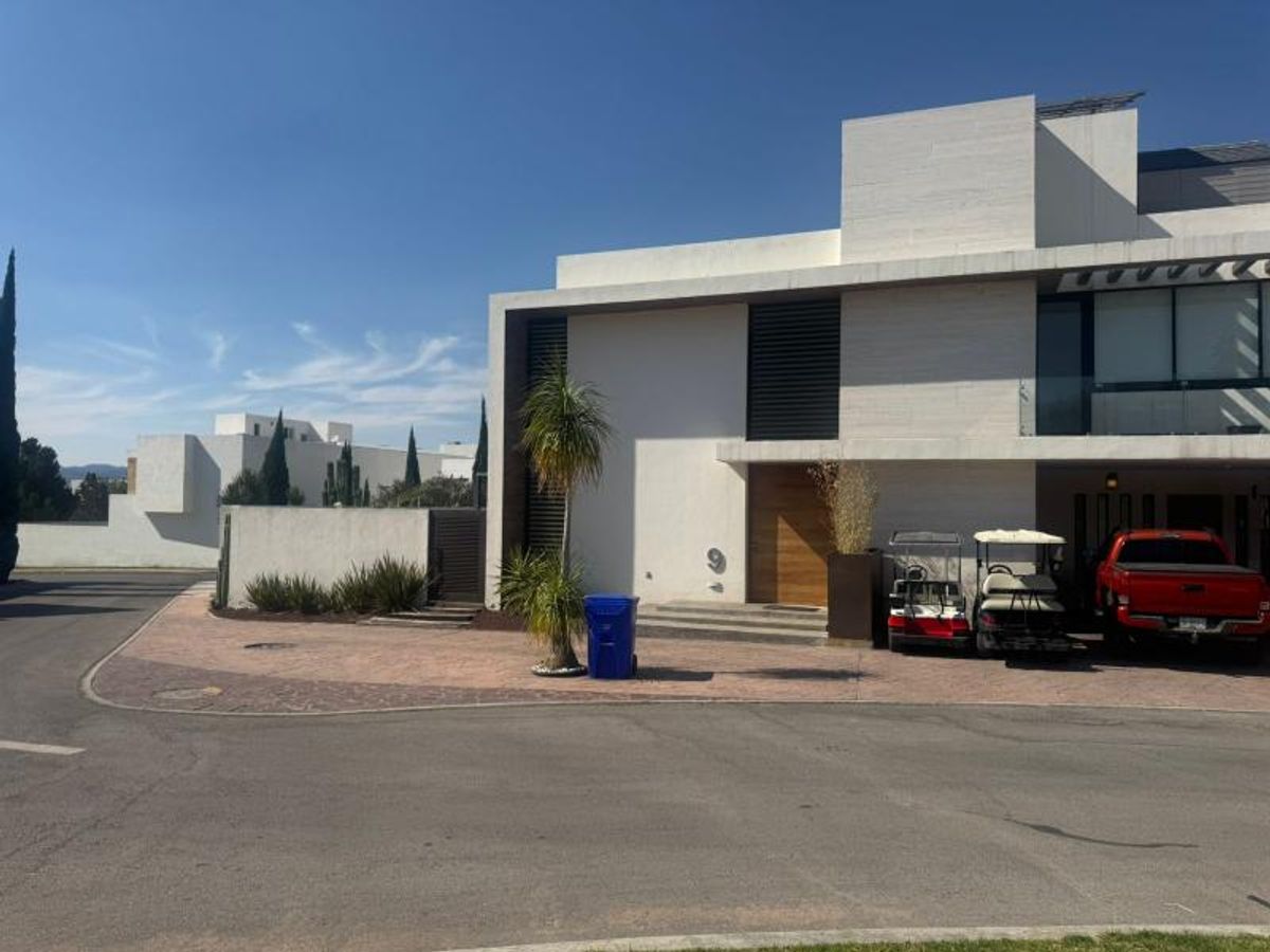 Fachada residencial moderna de dos niveles con puerta de madera y cochera pavimentada