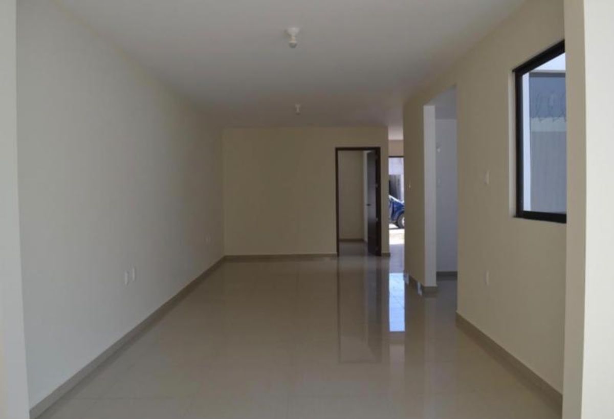 Espacio interior vacío con pisos de cerámica brillante, paredes beige claro y marcos oscuros