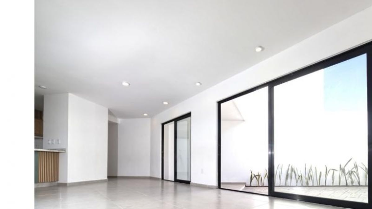 Espacio interior con piso claro, luces empotradas y ventanales corredizos hacia un patio