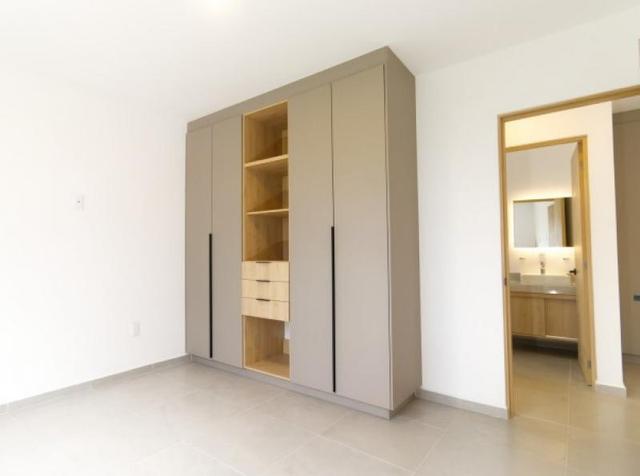 Habitación con clóset empotrado de tonos neutros y madera junto al baño privado