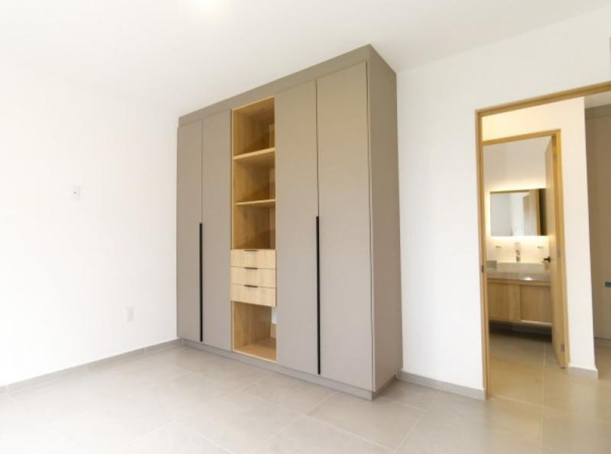 Habitación con clóset empotrado de tonos neutros y madera junto al baño privado