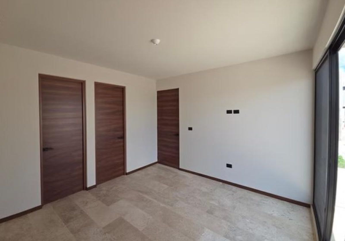 Interior vacío con piso de mármol, paredes claras y tres puertas de madera oscura