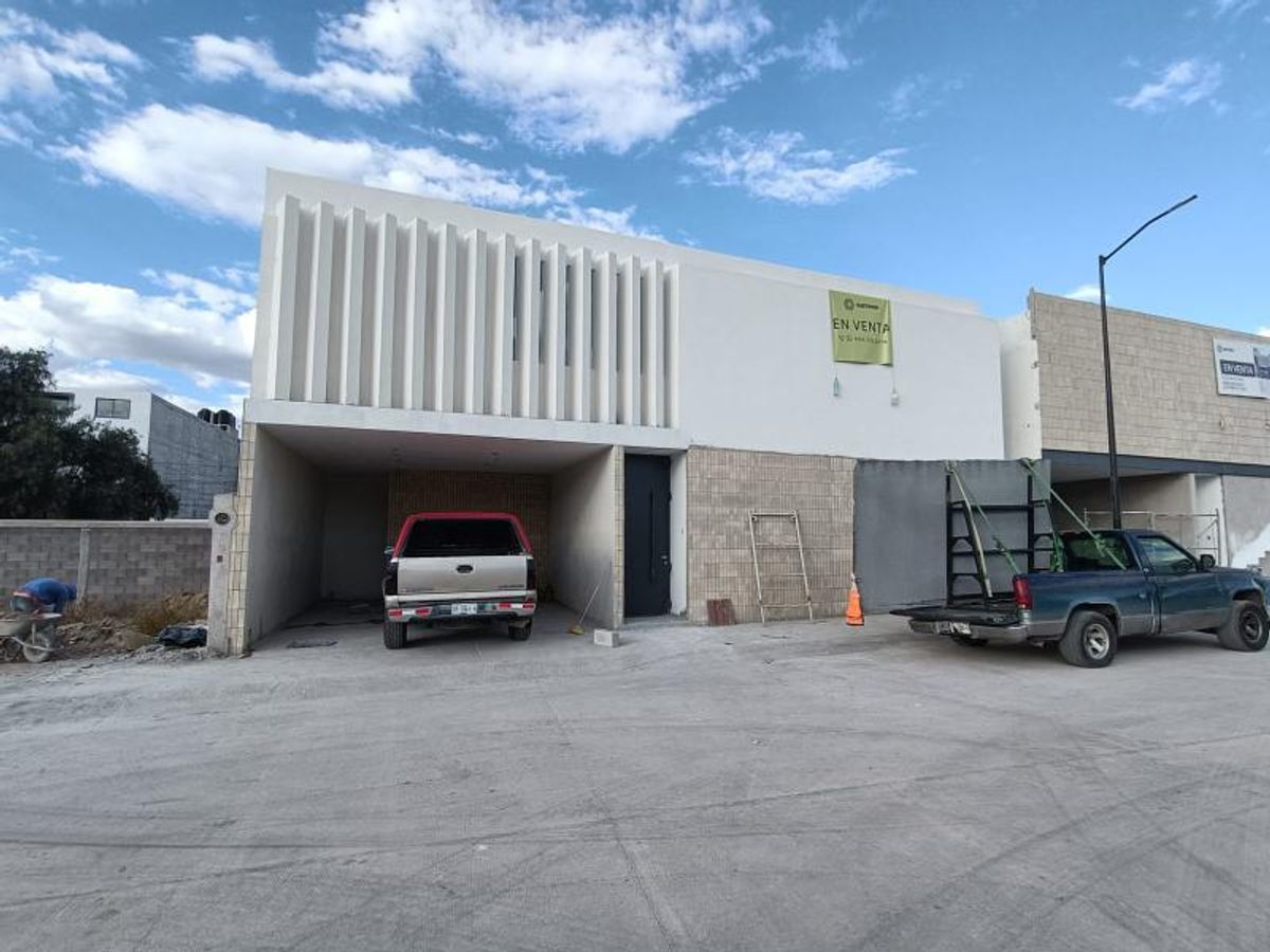 Fachada de casa con celosía vertical blanca, cochera techada y vehículos estacionados al frente