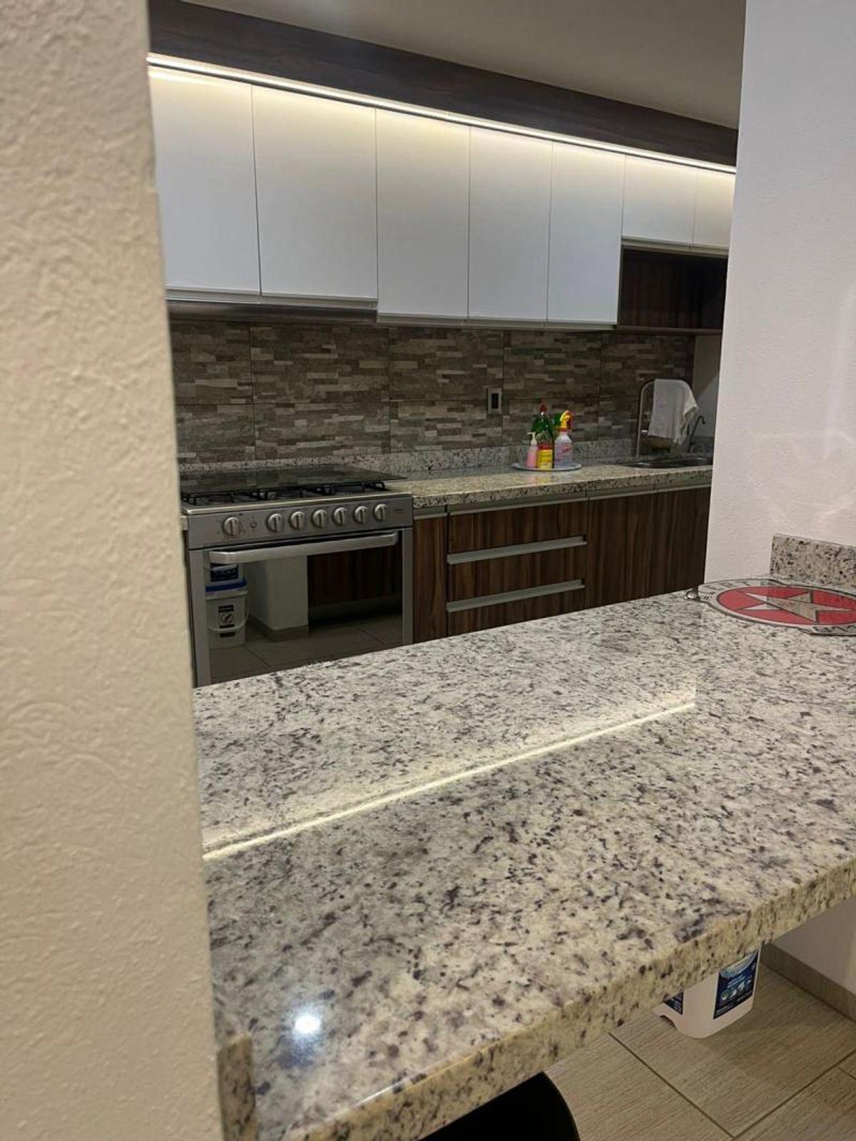 Cocina integral con barra de granito, estufa de acero inoxidable y gabinetes de madera