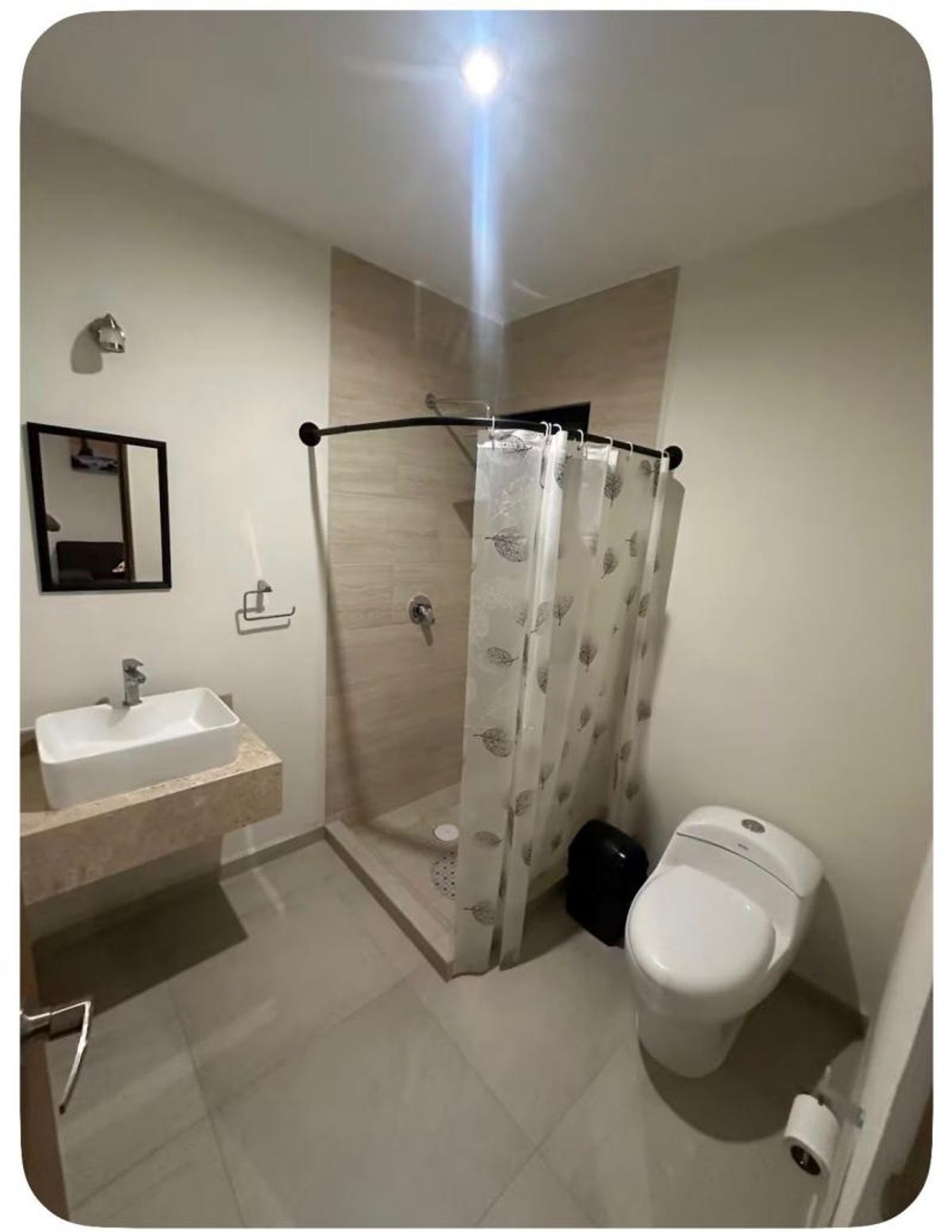 Baño con lavabo rectangular sobre cubierta beige, inodoro blanco y área de regadera azulejada
