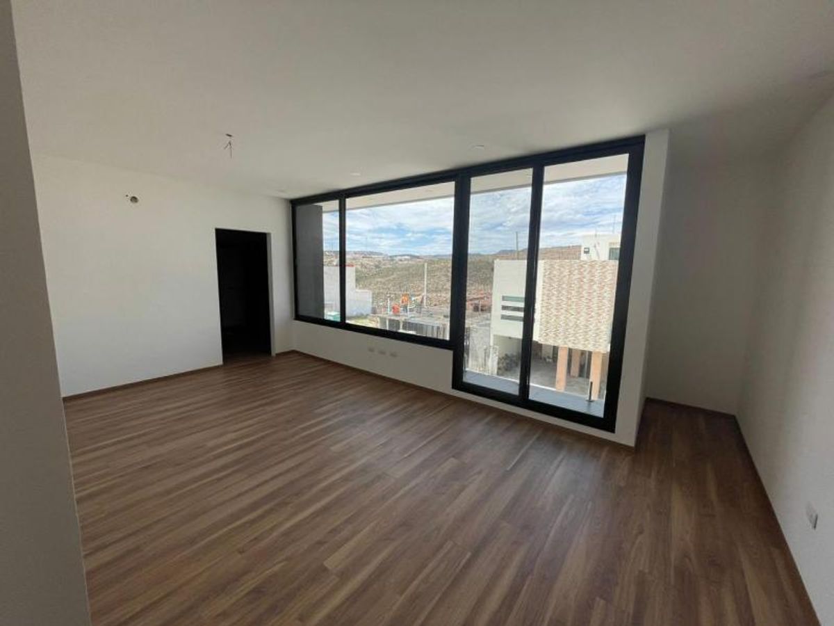 Habitación vacía con piso de acabado madera, paredes blancas y ventanales con marcos negros