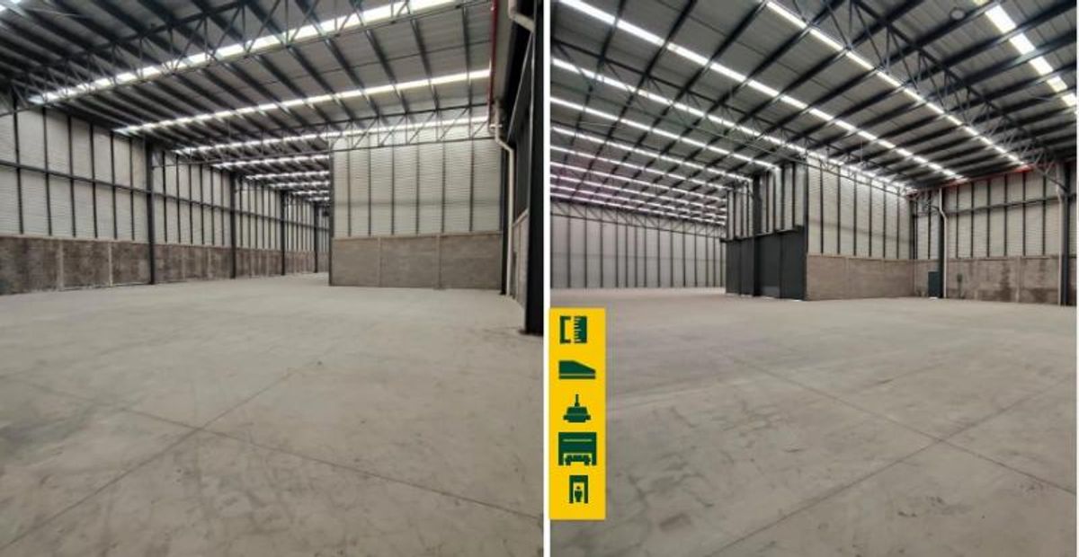 Interior de bodega industrial vacía con piso de concreto, techos altos metálicos y tragaluces
