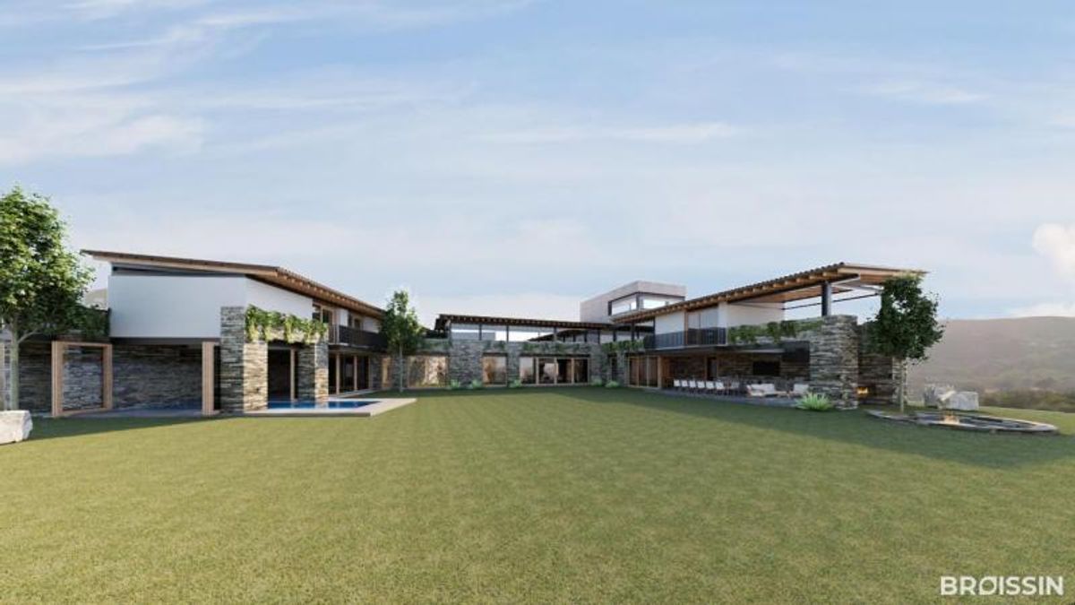 Casa moderna con fachada de piedra, techos de madera y un extenso jardín verde
