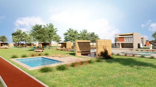 Área verde con piscina azul, camastros de madera, pérgola de piedra y pista roja