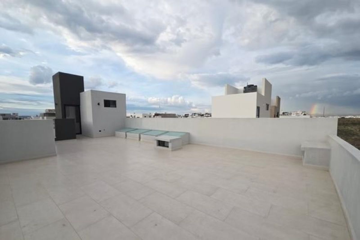 Terraza en azotea con piso de loseta clara, muros blancos y cubo de escaleras