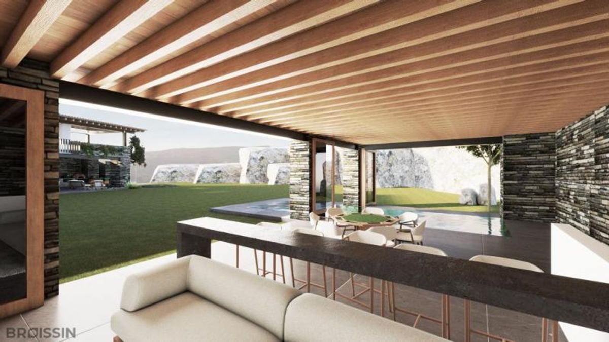 Terraza con vigas de madera, barra con bancos, sofá claro y vista al jardín
