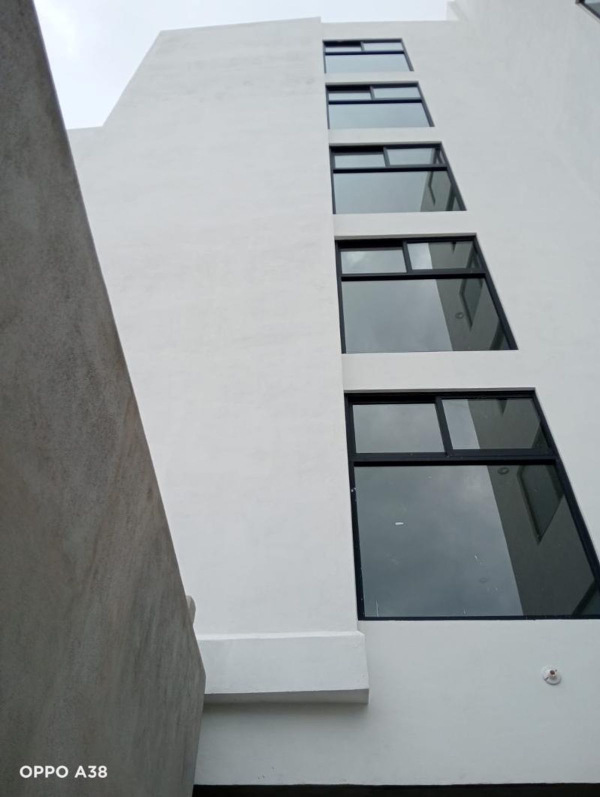 Fachada exterior de edificio blanco con ventanas rectangulares de marcos negros alineadas verticalmente