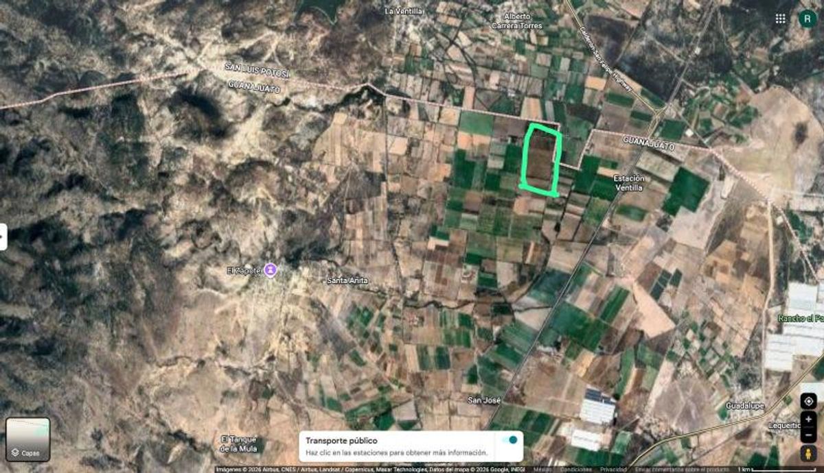 Terreno agrícola delimitado con marco verde rodeado de parcelas de cultivo y zonas montañosas
