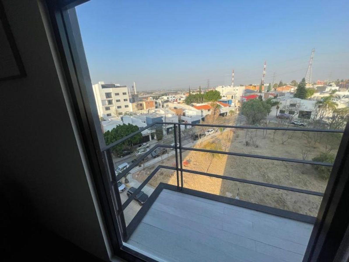 Balcón con barandal de metal negro, piso cerámico gris y vista hacia la ciudad
