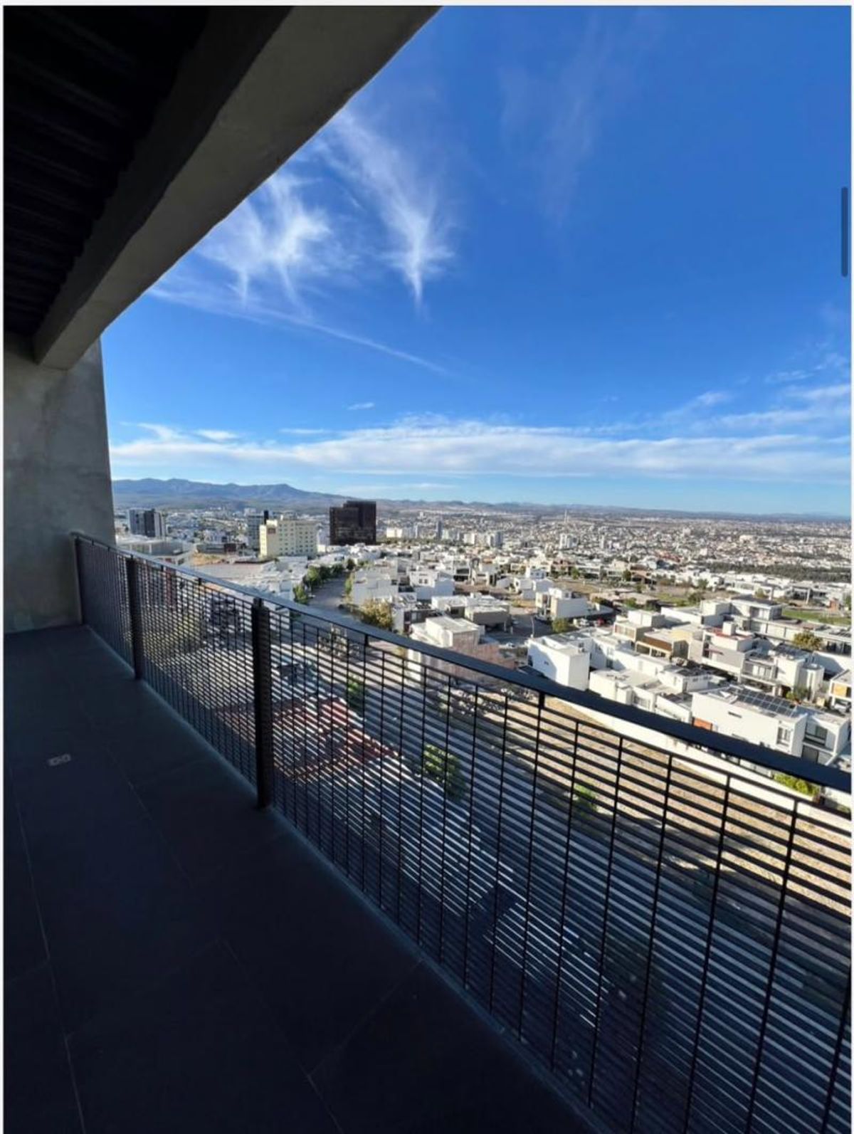Balcón con barandal metálico negro y vista panorámica hacia la ciudad y montañas