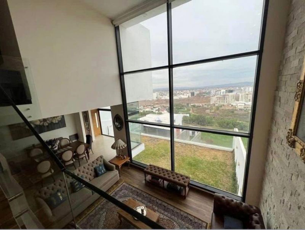 Sala de doble altura con ventanal de piso a techo y vista a la ciudad