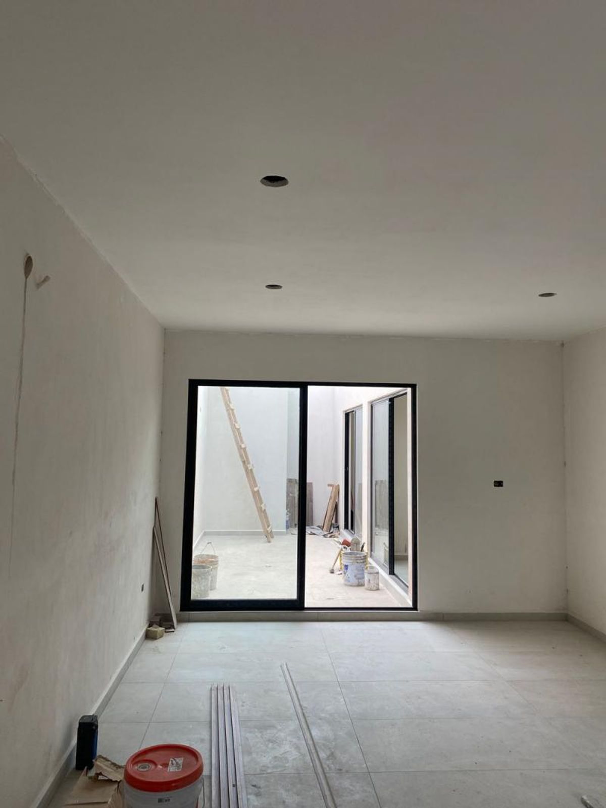 Habitación en construcción con pisos de cerámica claros y ventanal corredizo de marco negro