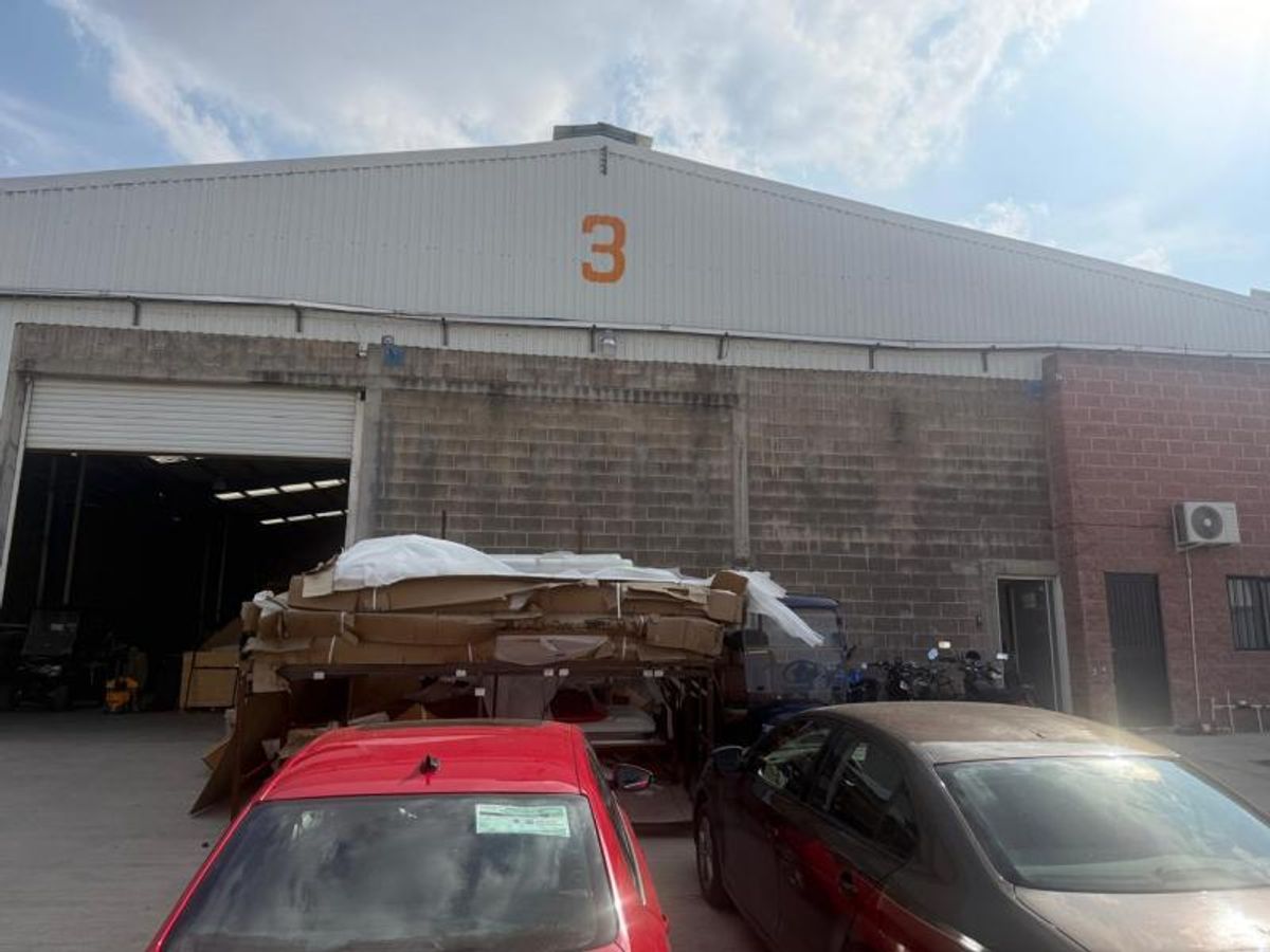 Fachada exterior de bodega con muros de concreto, lámina metálica y gran número tres
