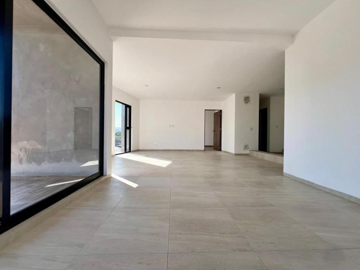 Espacio interior con piso de cerámica beige, paredes blancas y ventanales de marco negro