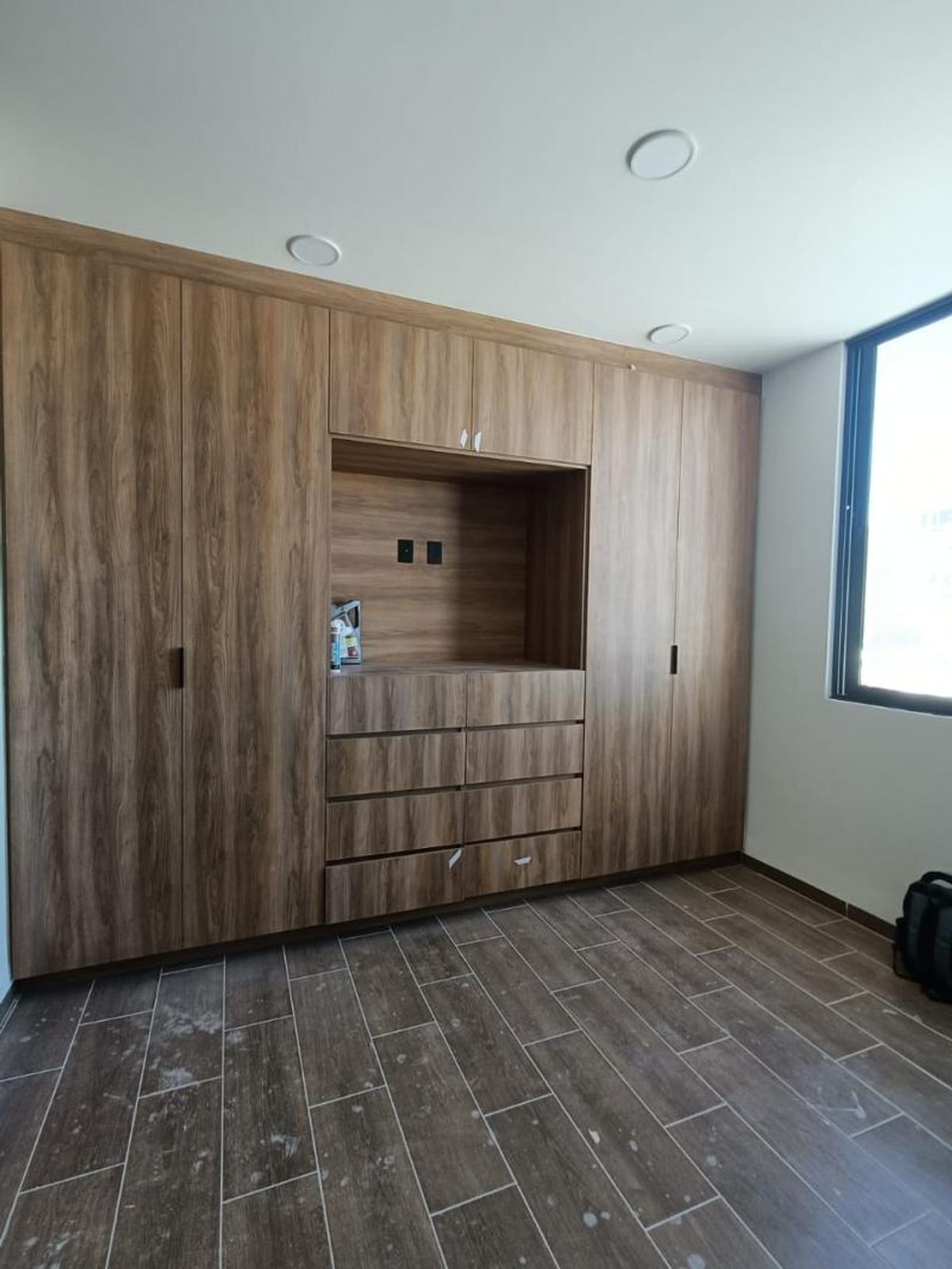 Closet de madera empotrado de piso a techo con cajonera central y piso cerámico