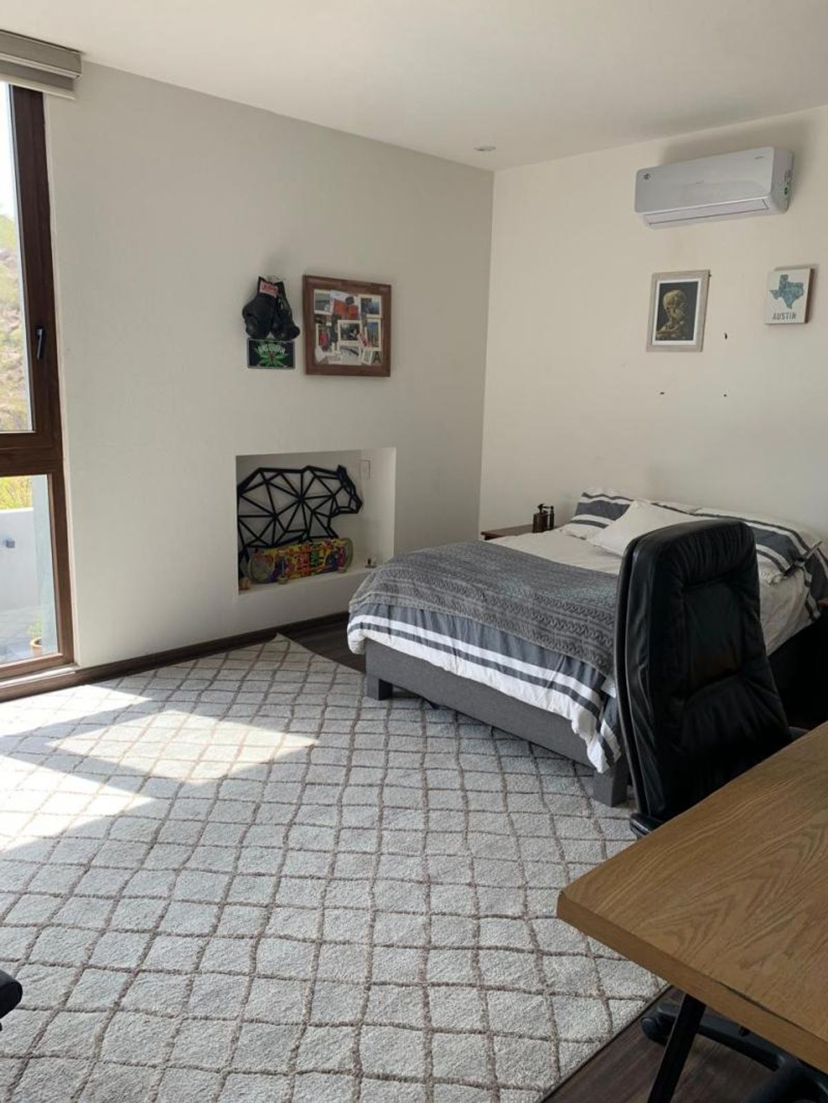 Recámara con cama, alfombra geométrica, nicho decorativo en pared y ventana amplia