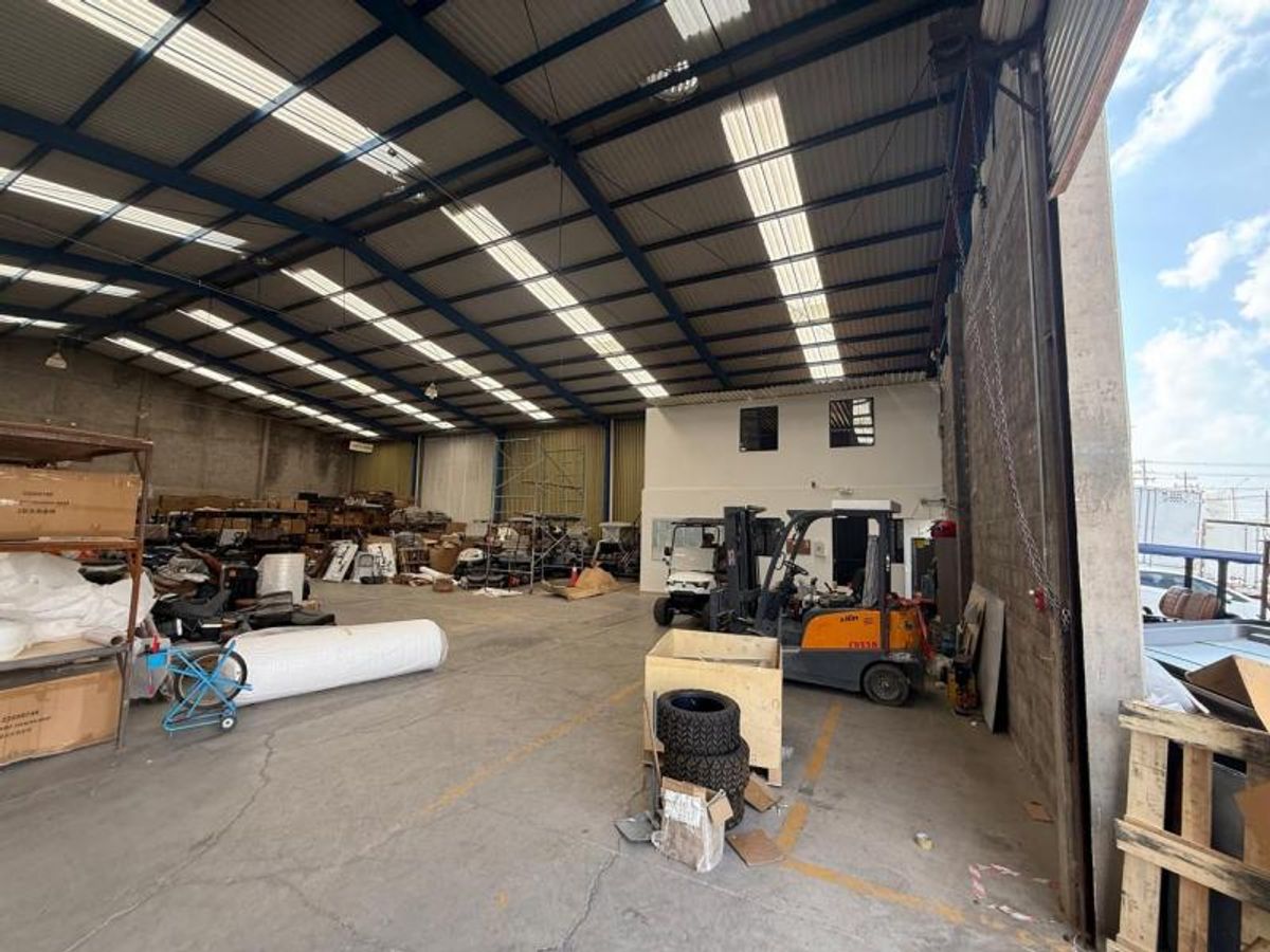 Interior de bodega industrial con estructura metálica, tragaluces en techo y piso de concreto