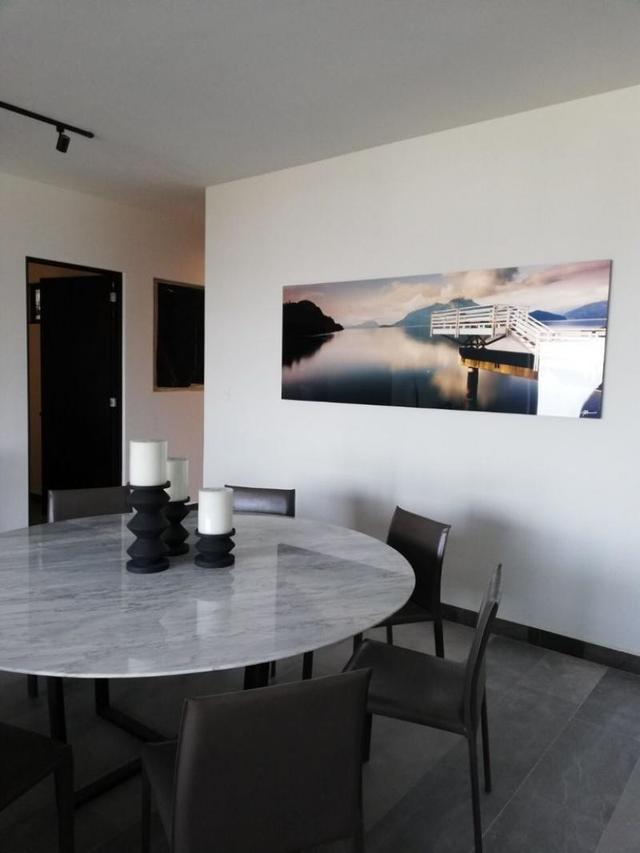 Comedor con mesa redonda de mármol gris, sillas oscuras y un cuadro panorámico